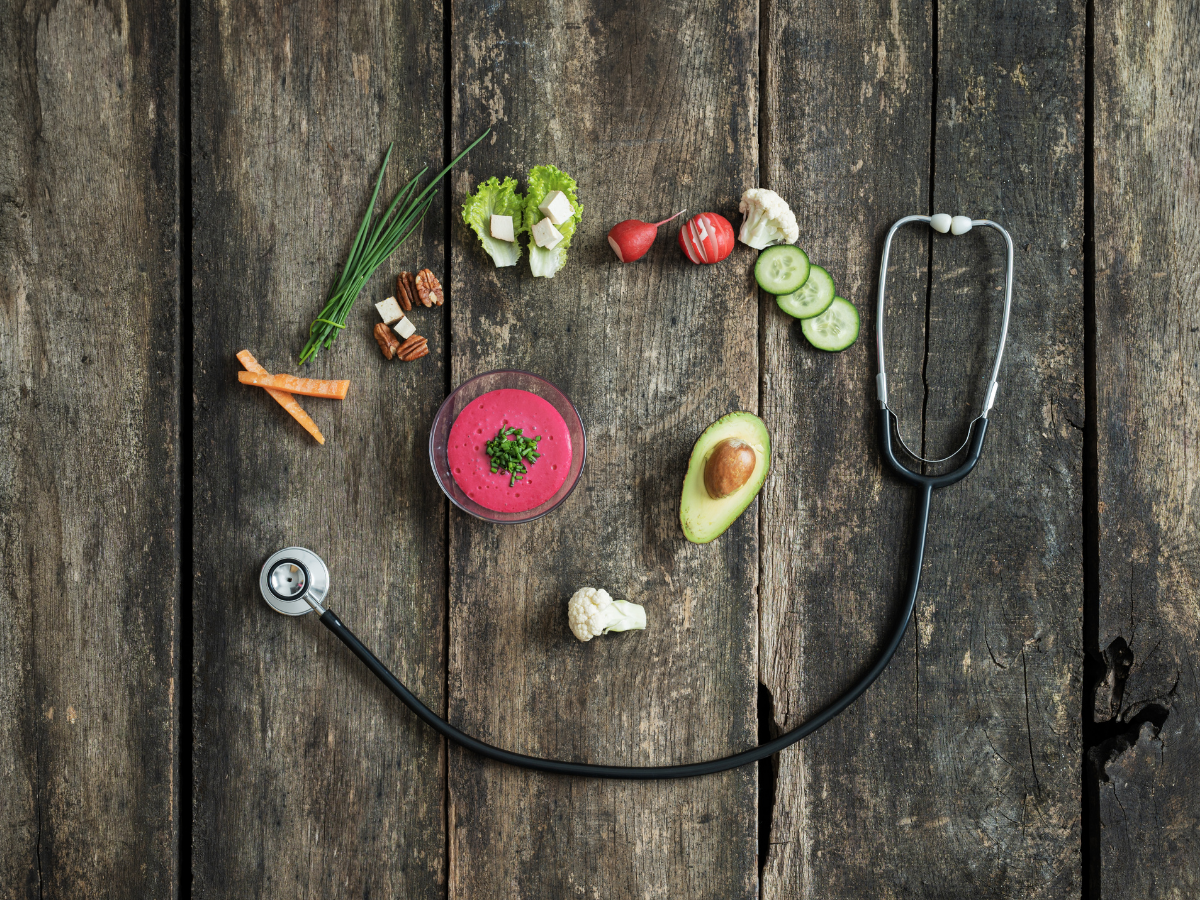 Healthy food and stethoscope forming a heart shape on rustic wooden table, symbolizing nutrition and heart health connection