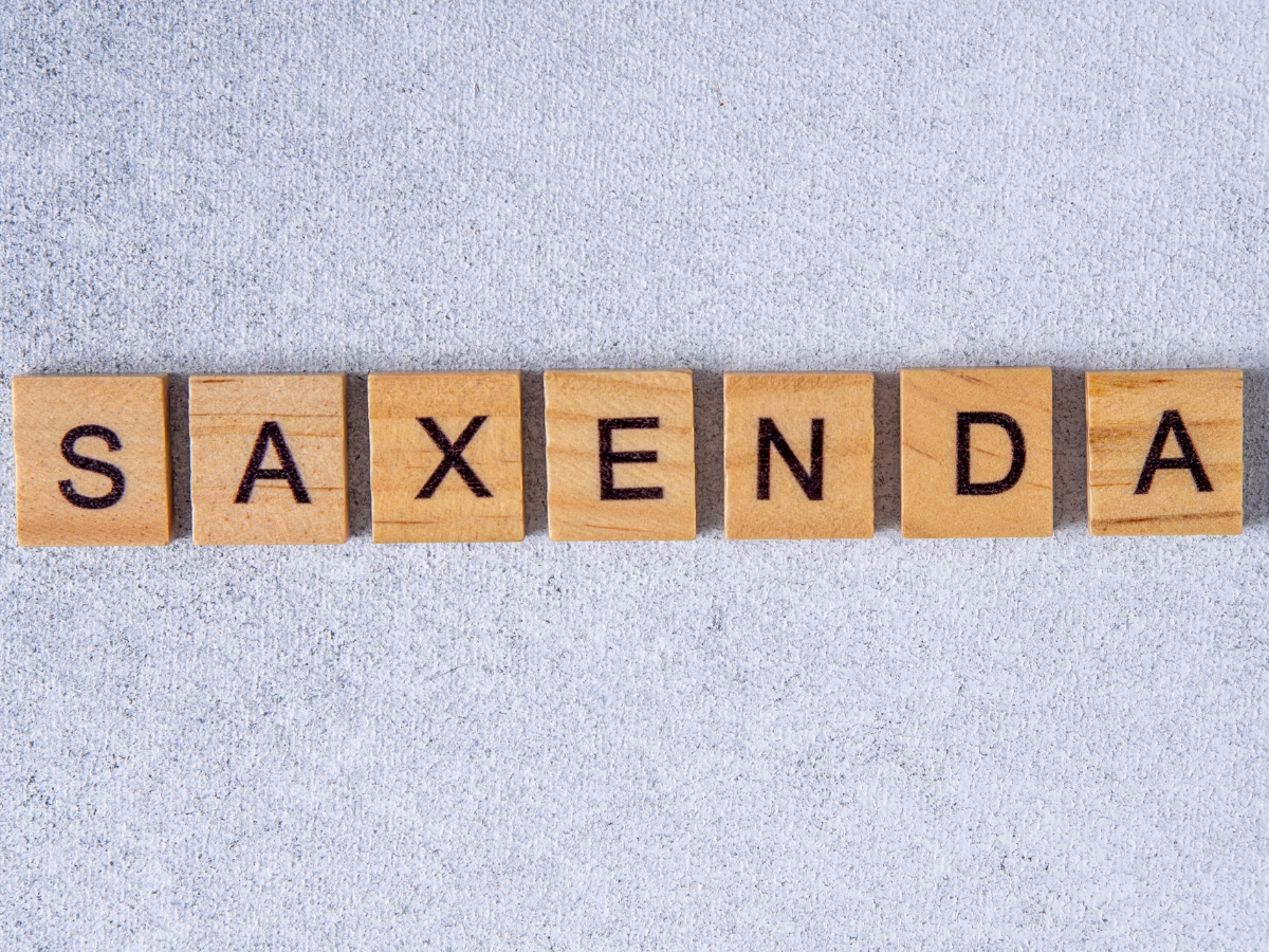 Scrabble-style wooden letter tiles spelling out “Saxenda” on a gray concrete background — referencing the popular weight loss injection featured on andyou.ph.